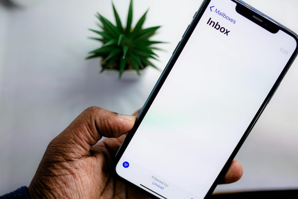 pexels-photo-5744250-5744250 A close-up view of a smartphone screen displaying the email inbox, held by an adult's hand.