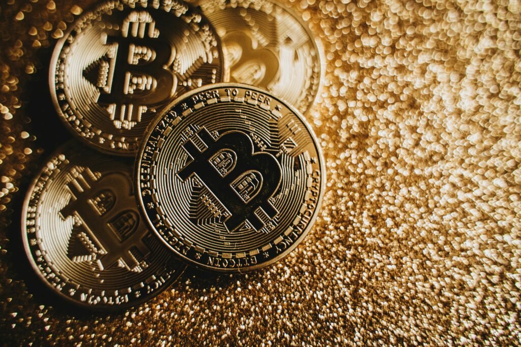 pexels-photo-6764683-6764683 Close-up of Bitcoin cryptocurrency coins on a sparkling gold glitter background, symbolizing digital finance.